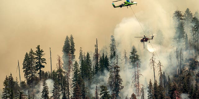 Seen from unincorporated Mariposa County, Calif., a helicopter drops water on the Washburn Fire burning in Yosemite National Park on Saturday, July 9, 2022. 