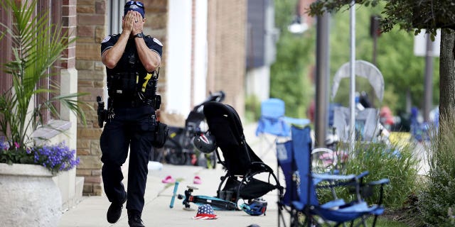 A Lake County, Illinois, police officer walks down Central Avenue in Highland Park on July 4, 2022, after a shooter fired on the northern suburb's Fourth of July parade. At least six people were killed and at least two dozen injured. (Brian Cassella/Chicago Tribune/Tribune News Service via Getty Images)