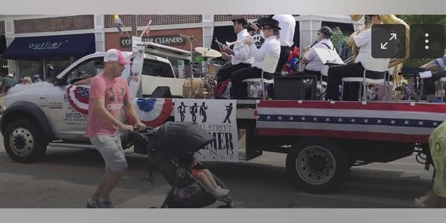 A Fourth of July parade-goer runs for cover after gunfire was heard at the parade Monday morning, July 4, 2022, in a suburb of Chicago. (Lynn Sweet/Chicago Sun-Times via AP)