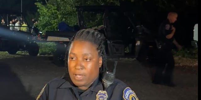 An Indianapolis police officer updates the media at the scene where four bodies were found in a pond Tuesday night. 