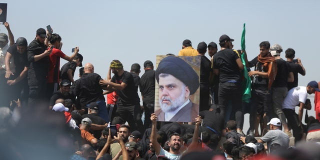 A protester holds a poster depicting Shiite cleric Muqtada al-Sadr on a bridge leading toward the Green Zone area in Baghdad, Iraq, July 30, 2022.