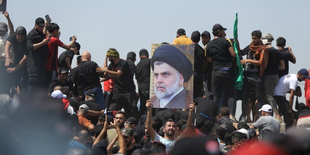 A protester holds a poster depicting Shiite cleric Muqtada al-Sadr on a bridge leading toward the Green Zone area in Baghdad, Iraq, July 30, 2022.