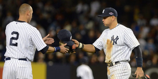 Alex Rodriguez, #13 of the New York Yankees, hands Derek Jeter, #2, his baseball hat and glove during Game One of the American League Championship Series against the Detroit Tigers at Yankee Stadium on October 13, 2012 in the Bronx borough of New York City, New York. The Tigers defeated the Yankees 6-4 in 12 innings.