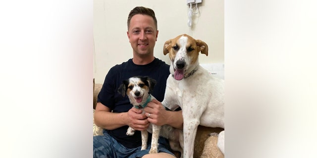 Chief Petty Officer Matt Johnson sits with his two rescue dogs, Ruby and Sunny.