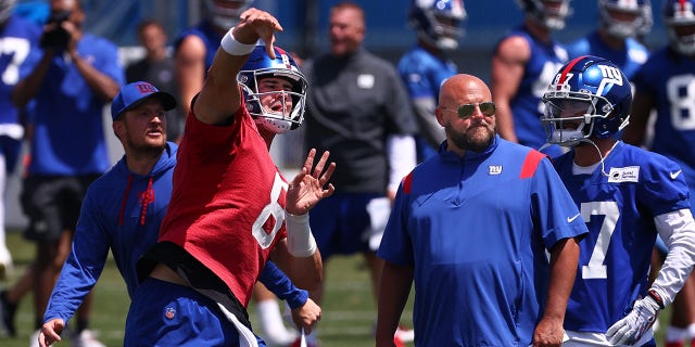 Quarterback Daniel Jones #8 of the New York Giants throws a pass as head coach Brian Daboll, right, looks on during mandatory minicamp at Quest Diagnostics Training Center on June 8, 2022 in East Rutherford, New Jersey.