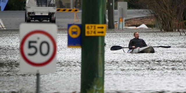 A man paddles his kayak through a flooded street at Windsor on the outskirts of Sydney, Australia, Tuesday, July 5, 2022. Hundreds of homes have been inundated in and around Australia's largest city in a flood emergency that was impacting 50,000 people, officials said Tuesday. 