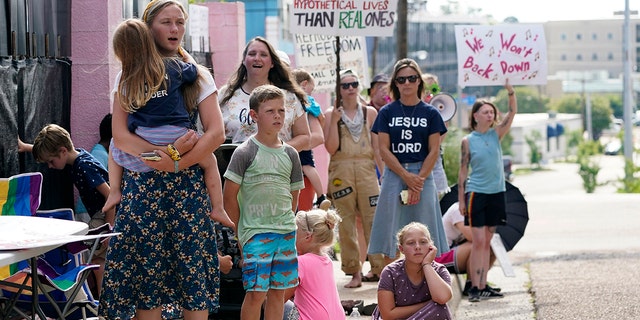 Pro-life supporters and their children, in the foreground, sing religious songs as pro-choice supporters wave their signs and shout to be heard above the chant, as they all stand outside the clinic in the Jackson Women's Health Organization in Jackson, Miss., Thursday, July 7, 2022.