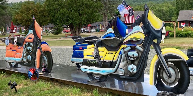Motorcycle likenesses, part of a memorial to honor members of the Jarheads Motorcycle Club killed in a nearby crash, are visible July 13, 2022, on the roadside in Randolph, N.H. Volodymyr Zhukovskyy, of West Springfield, Mass., is scheduled to face trial on July 26, 2022, on multiple counts of negligent homicide, manslaughter, driving under the influence and reckless conduct stemming from the crash that killed seven motorcyclists that happened in Randolph on June 21, 2019.