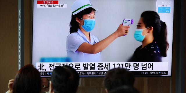 People watch a TV broadcasting a news report on the COVID-19 outbreak in North Korea, at a railway station in Seoul, South Korea, on May 17, 2022.