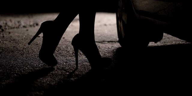 Silhouette of legs in high heels coming to car.