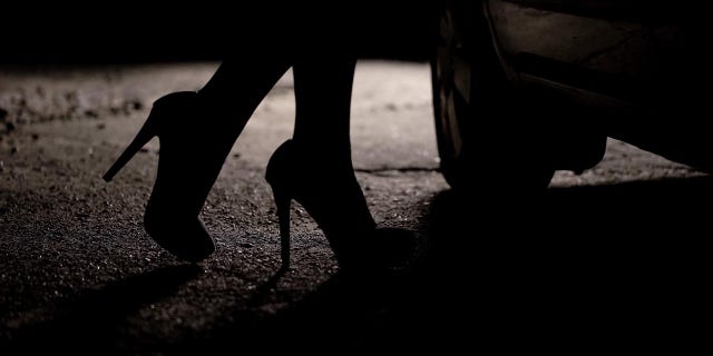 Silhouette of legs in high heels coming to car.