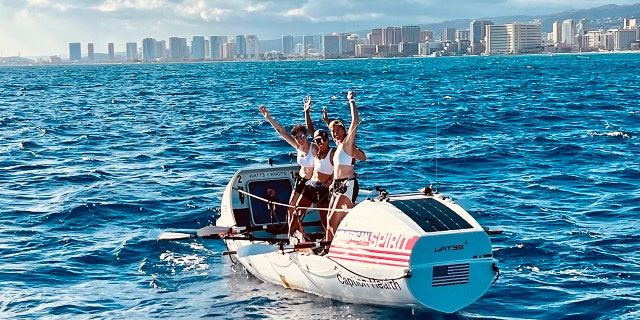Lat35 rowers Libby Costello, Sophia Denison-Johnston, Brooke Downes and Adrienne Smith cheer across the finish line of the Great Pacific Race on July 25, 2022 in Waikiki, Hawaii.