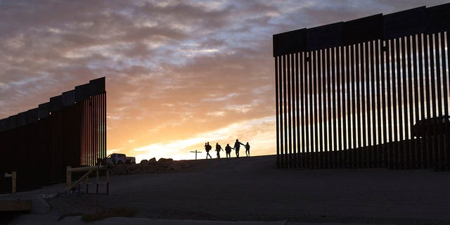 FILE - Các gia đình nhập cư từ Brazil vượt qua một khoảng trống trên bức tường biên giới để đến Hoa Kỳ sau khi vượt từ Mexico đến Yuma, Arizona, để xin tị nạn.