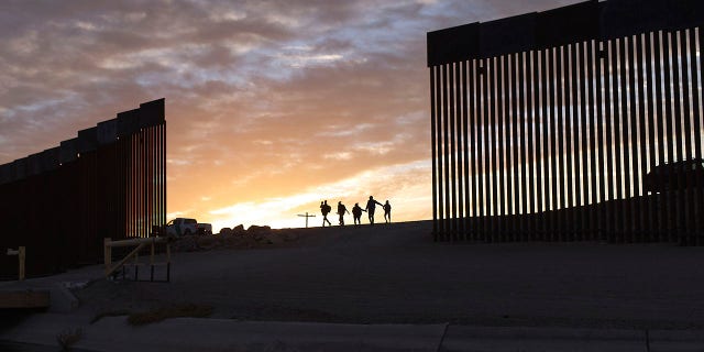 ARQUIVO - Famílias de imigrantes do Brasil passam por uma brecha no muro da fronteira para chegar aos Estados Unidos após cruzarem do México para Yuma, no Arizona, em busca de asilo.