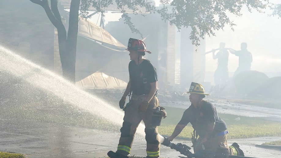 Two firefighters using a water hose in Texas near Dallas