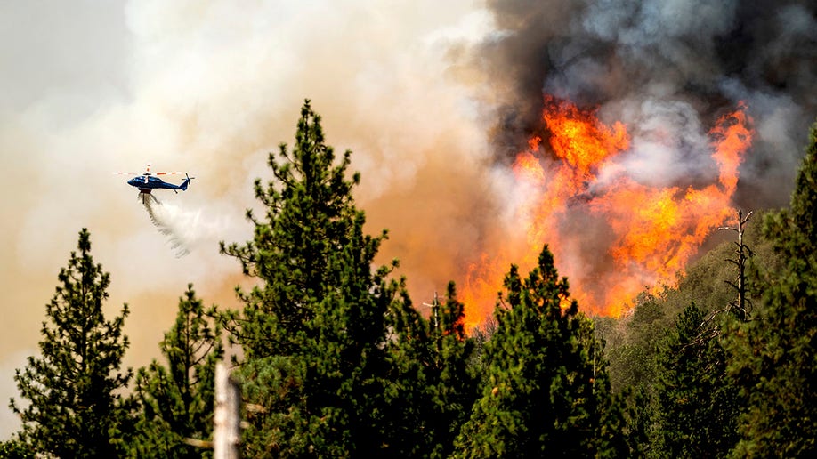 Helicopter dumping fire retardant on Oak Fire