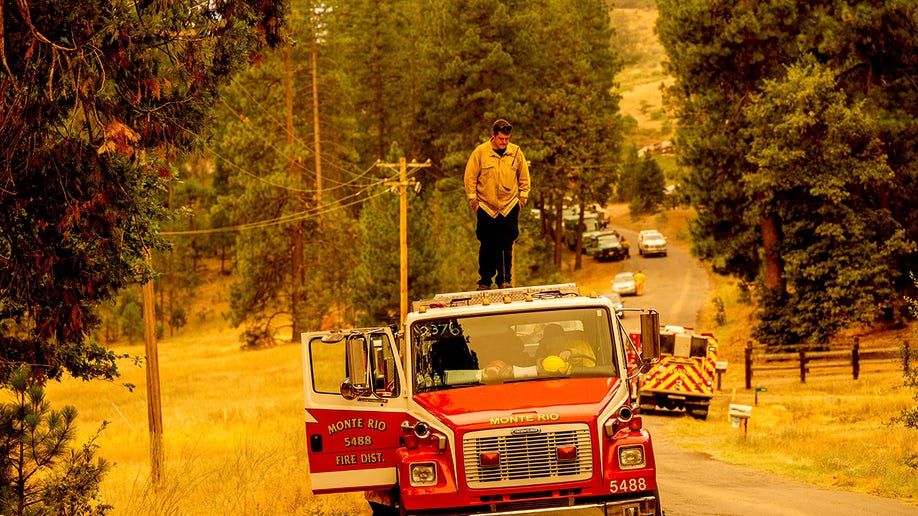 Firefighter standing on top of fire truck while battling the Oak Fire in California