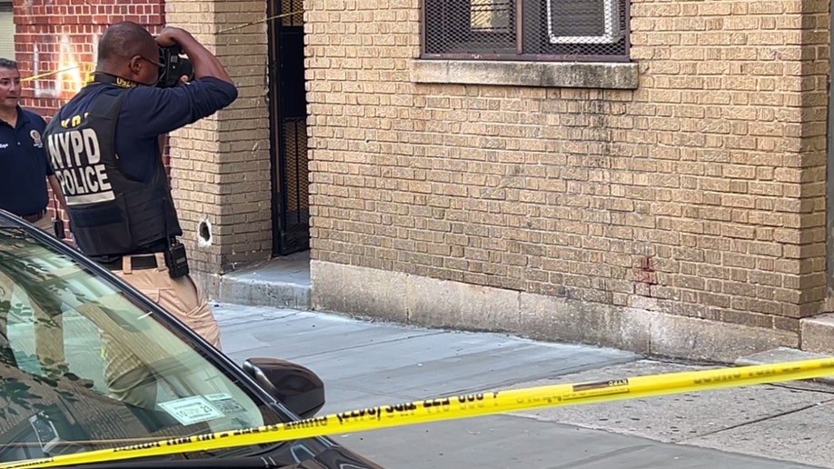 An NYPD officer photographs a spot of red on a wall at the scene of Nathaniel Rivers' fatal stabbing