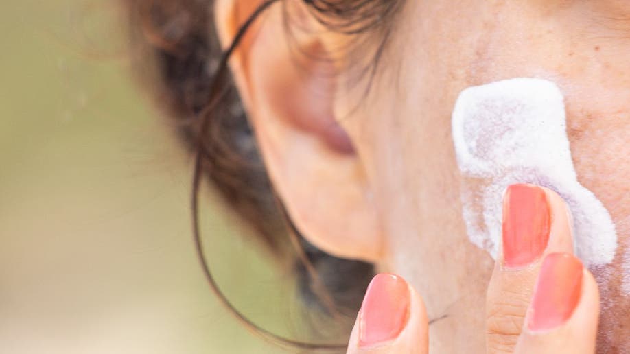 Woman rubs sunscreen on face