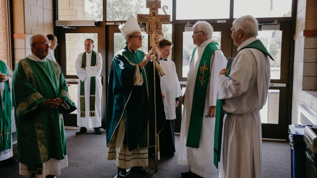 Bishop Barron speaking with priests before mass