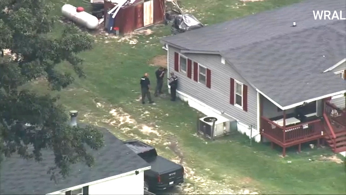 Three law enforcement officials are seen outside a North Carolina home