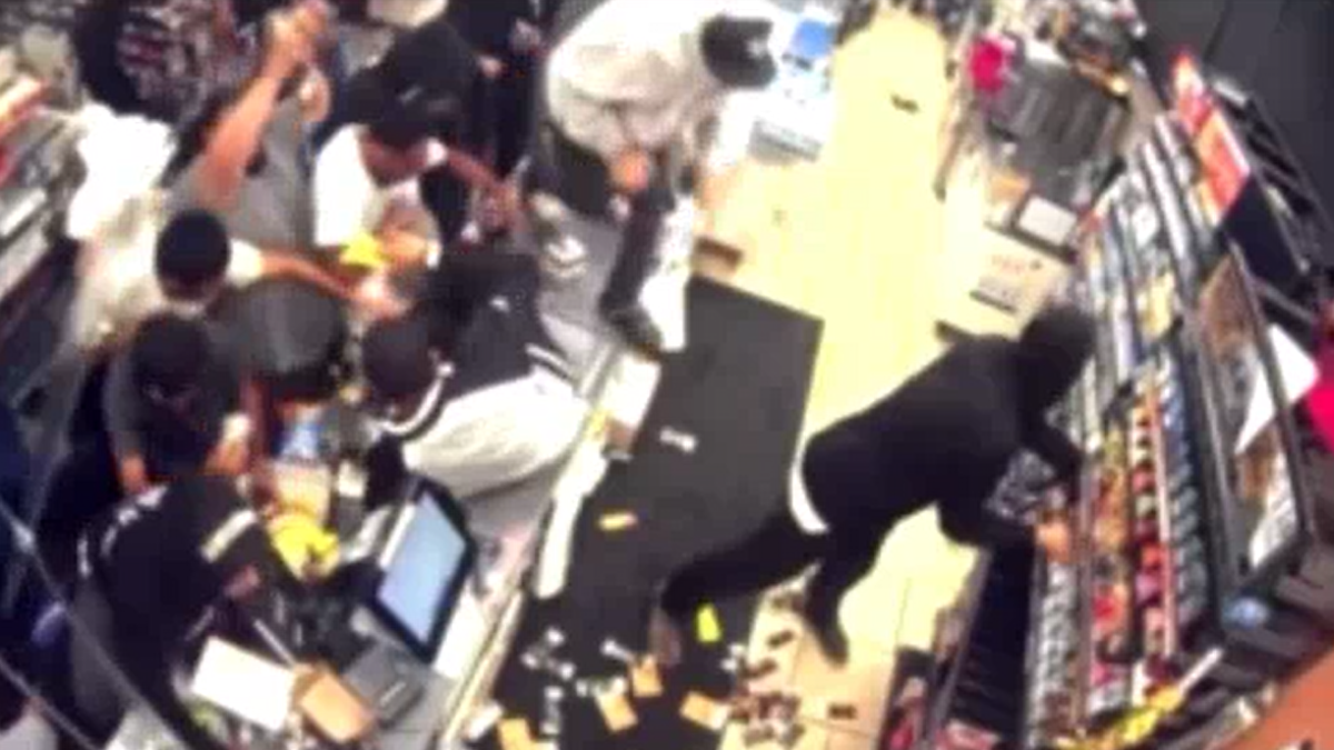 Photo shows a still from a video of a Los Angeles 7-Eleven looting, including people reaching over what appears to be the checkout counter