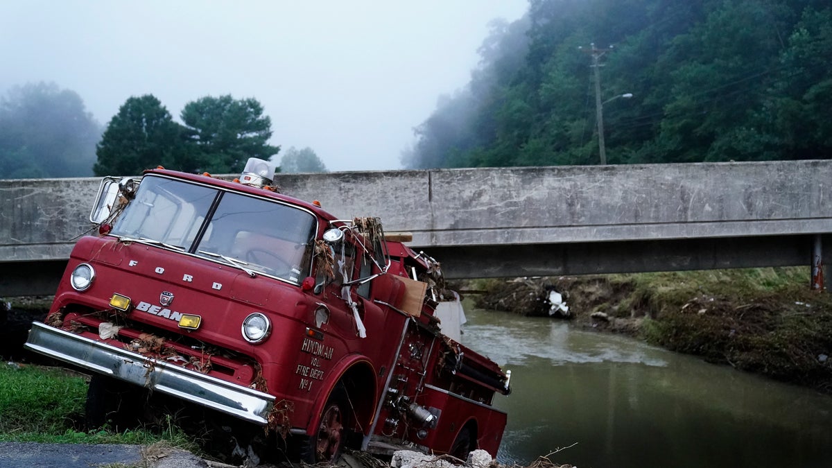 A fire truck is seen hangin over the edge of the water 