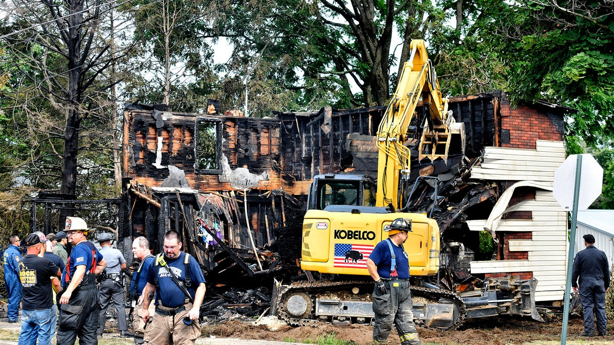 Crews work to demolish a house that was destroyed by a fatal fire