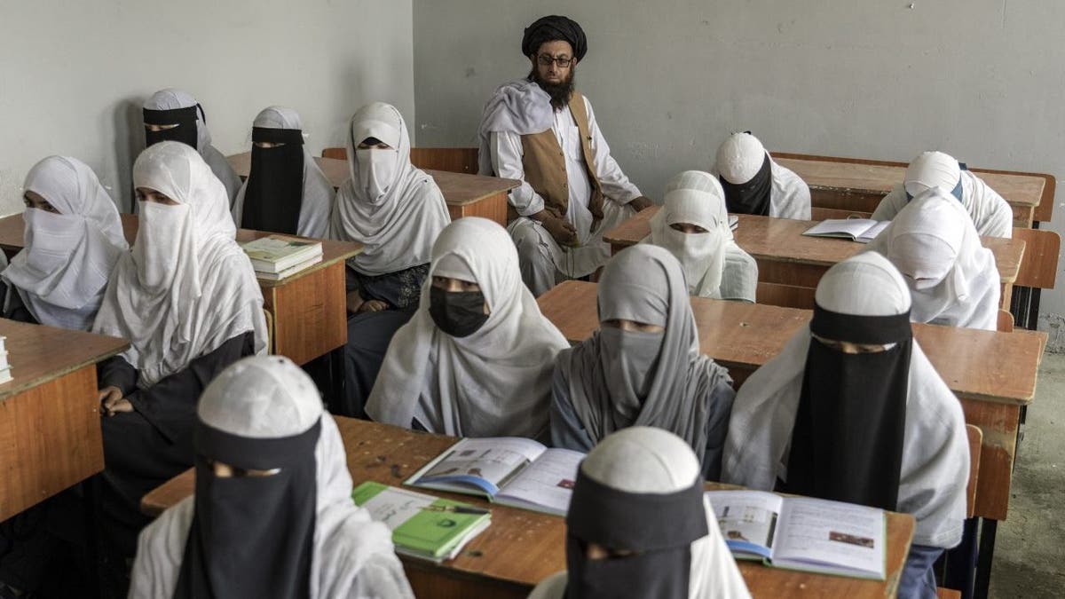 Girls wearing burqas study at a school in Afghanistan