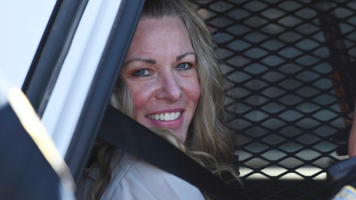 Lori Vallow Daybell smiling in back of police car 