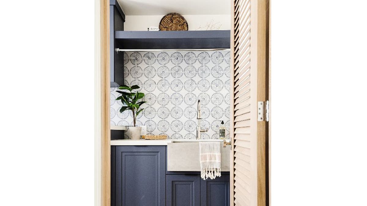 Laundry room with wallpaper and shelving