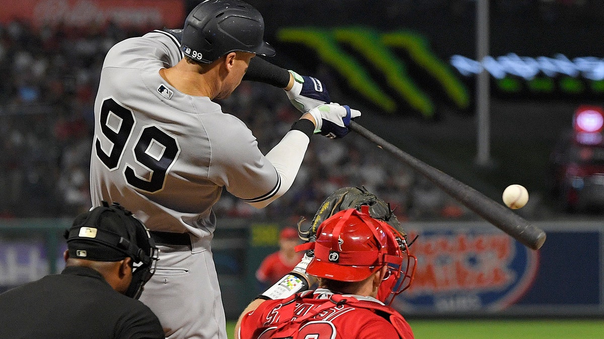 New York Yankees' Aaron Judge, center, hits a three-run home run as Los Angeles Angels catcher Max Stassi, right, watches along with home plate umpire Alan Porter during the fourth inning of a baseball game Tuesday, Aug. 30, 2022, in Anaheim, California. (AP Photo/Mark J. Terrill)
