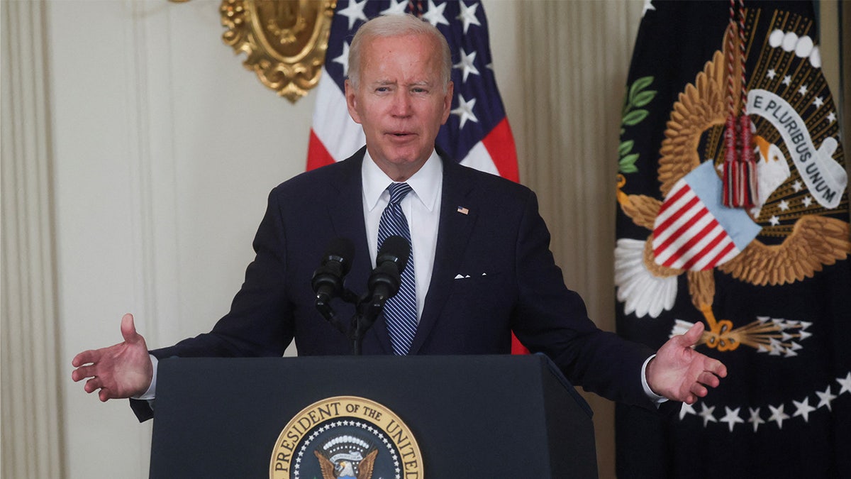 Joe Biden in a suit with a striped tie speaking at podium behind the presidential seal