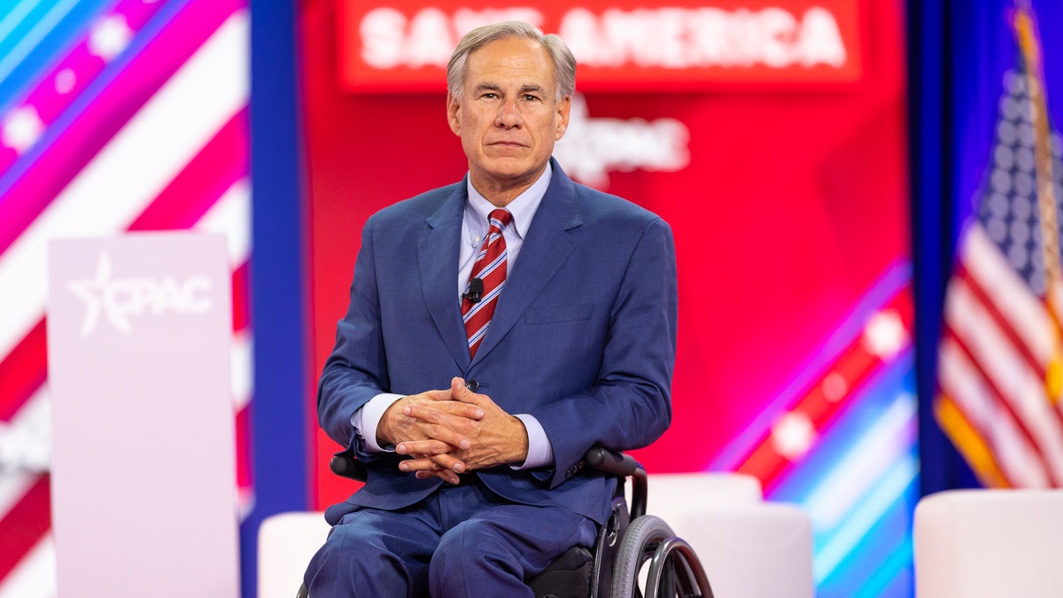 Greg Abbott in a blue suit and striped red tie at CPAC Dallas 2022
