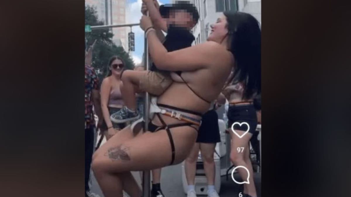 Woman dancing on stripper pole with child at Charlotte Pride Event
