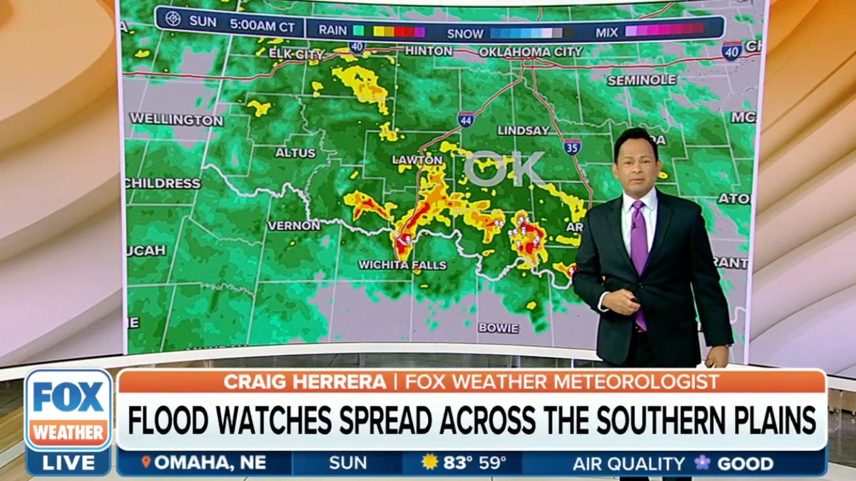 Weather man standing in front of map showing rain