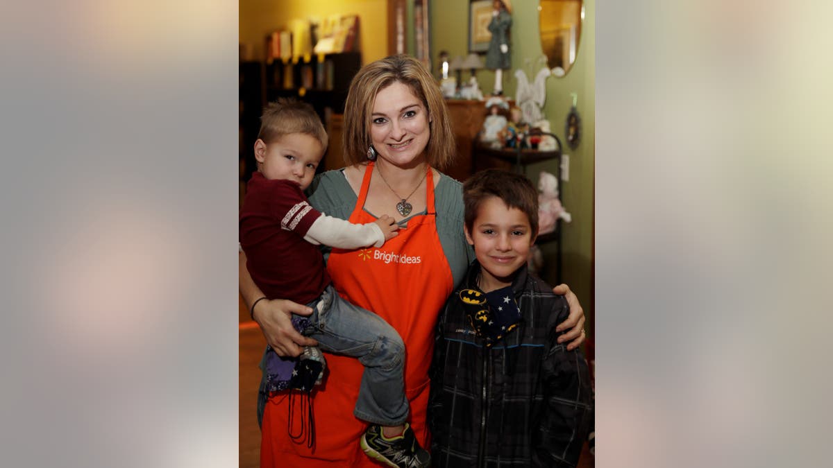 A mother in a red apron and her two boys receive food at Feeding South Dakota