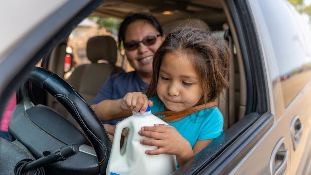 Food bank clients, a mother and daughter, open milk at Feeding South Dakota