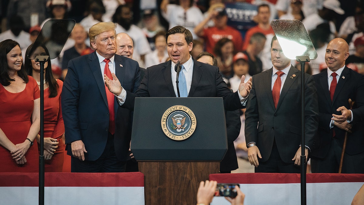 Trump standing behind Ron DeSantis on stage