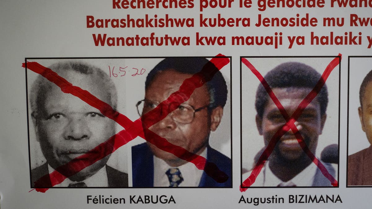 A red cross is seen drawn on the face of Augustin Bizimana (R), one of the most-wanted fugitives from the 1994 Rwandan genocide, next to the red-crossed face of Felicien Kabuga (L), who was arrested last week in Paris, on a wanted poster at the Genocide Fugitive Tracking Unit office in Kigali, Rwanda, on May 22, 2020.