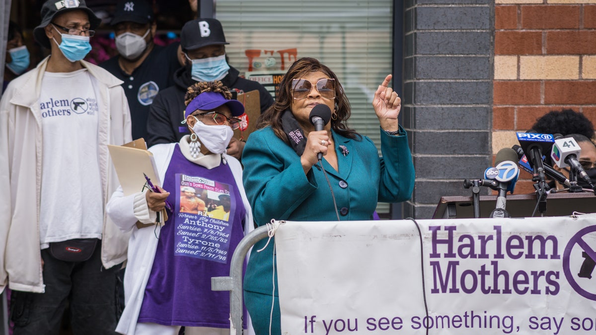 NY Assemblywoman Inez Dickens speaks at a rally in Harlem with masked supporters