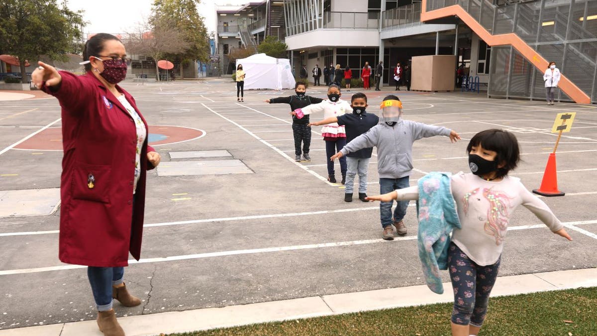 LA Unified teacher instructs masked children outside on playground