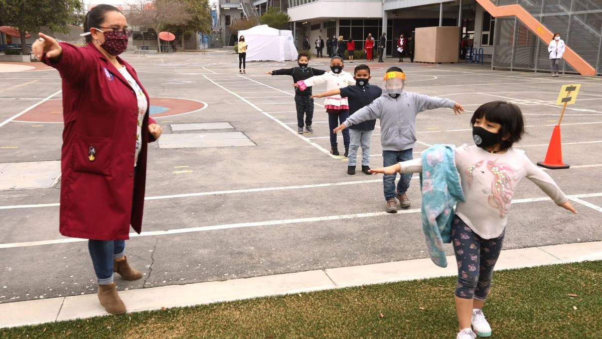 LA Unified teacher instructs masked children outside on playground