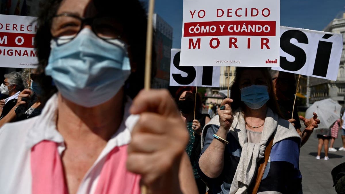 Spanish protesters with signs rally in support of euthanasia law