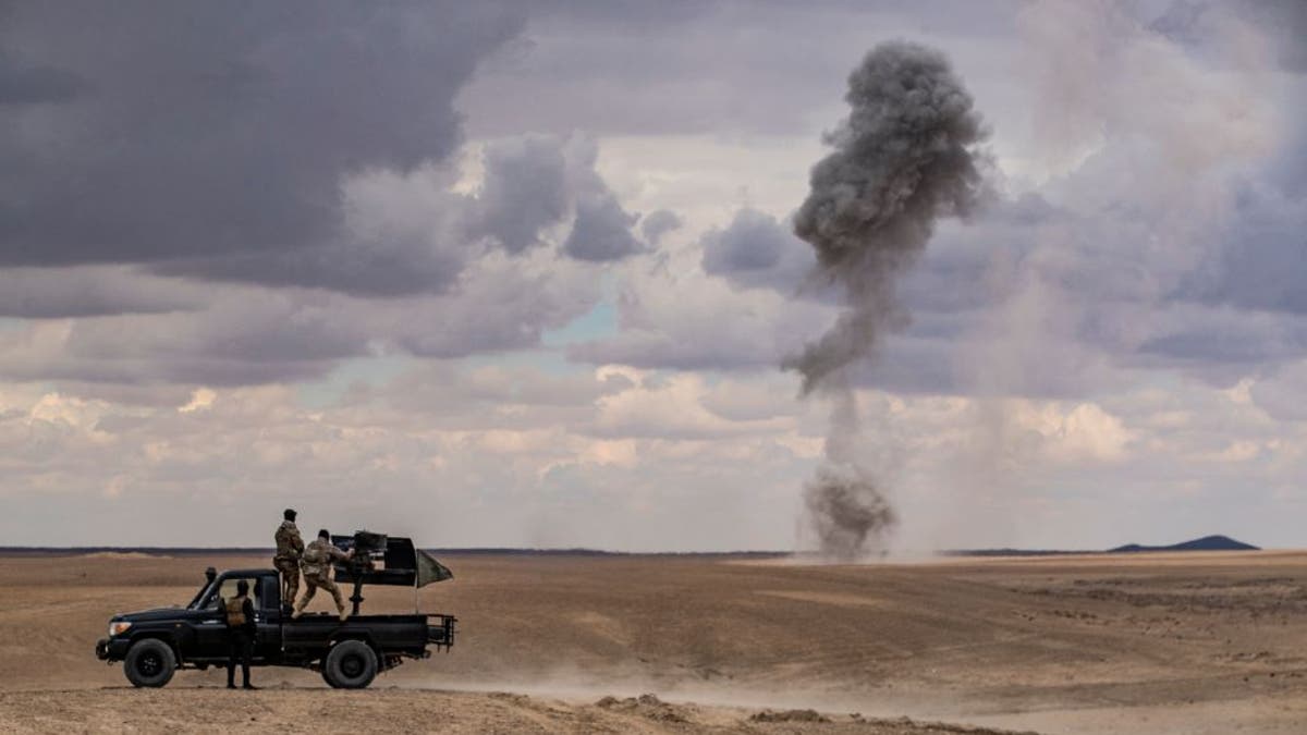 A truck with smoke in the distance in Syria