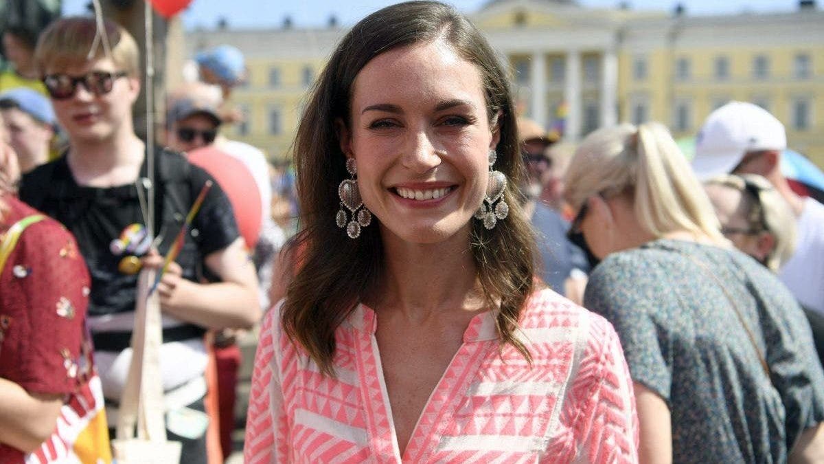 Sanna Marin wears a pink dress in a crowd of people