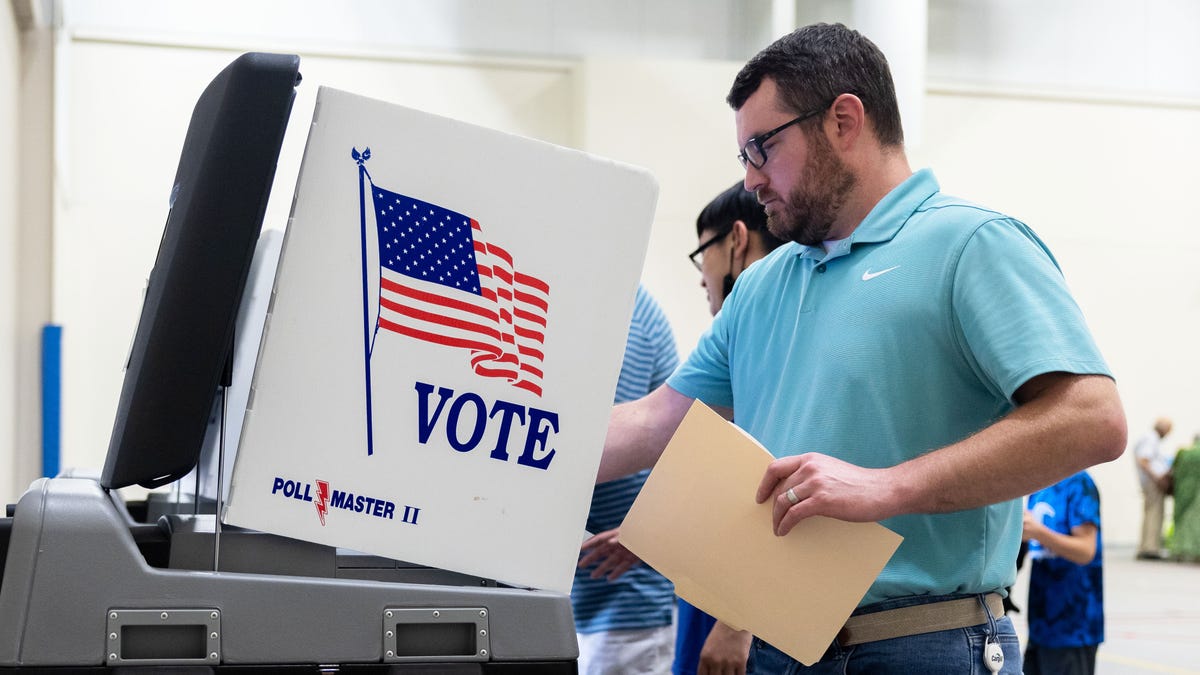 A man in a blue shirt casts his ballot