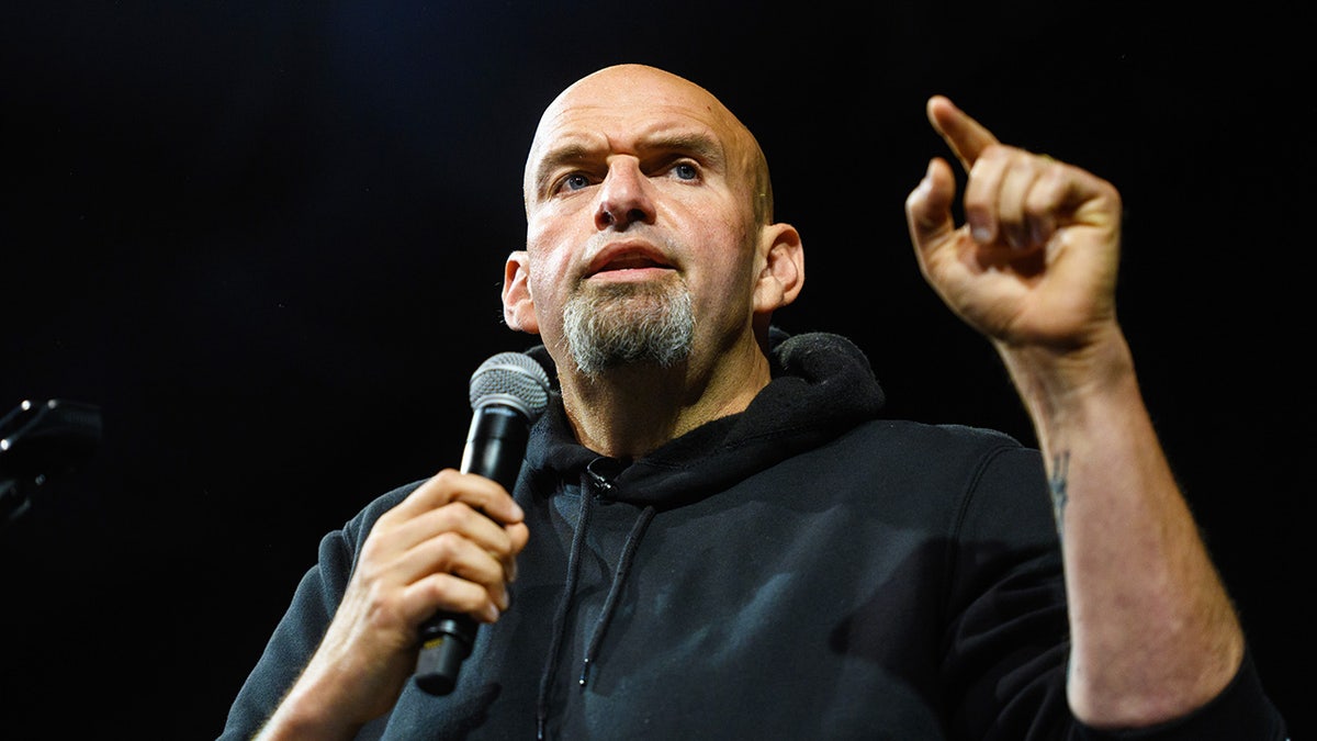 John Fetterman wearing a black hoodie and a holding a mic