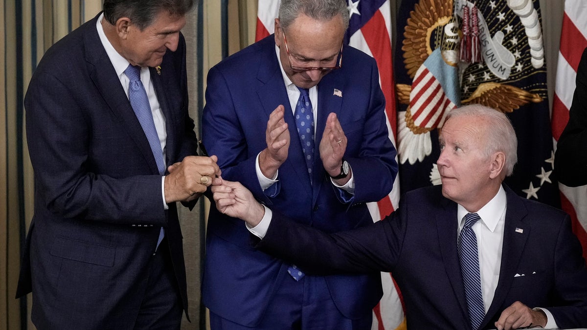 President Joe Biden (R) gives Sen. Joe Manchin (D-WV) (L) the pen he used to sign The Inflation Reduction Act