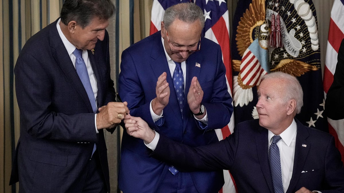 President Joe Biden (R) gives Sen. Joe Manchin (D-WV) (L) the pen he used to sign The Inflation Reduction Act. federal debt $31 trillion